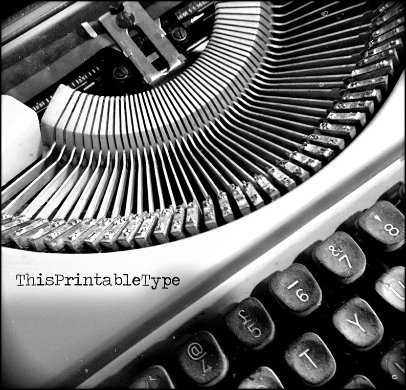 May include: Black and white close-up image of a vintage typewriter with the text "ThisPrintableType" on the front. The keys are visible and include numbers, symbols, and letters.
