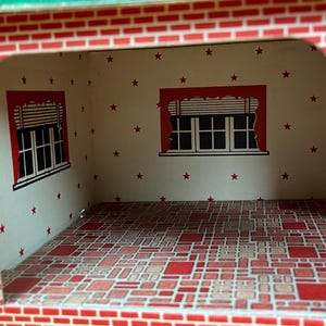May include: A dollhouse room interior featuring white walls with a red star pattern, two windows with red valances and blinds, and a floor covered in a red and tan geometric tile pattern. The exterior frame is printed with a red brick design.