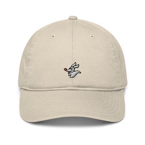 May include: A beige baseball cap with an embroidered white ghost character with a red nose. The ghost is from the movie "The Nightmare Before Christmas".