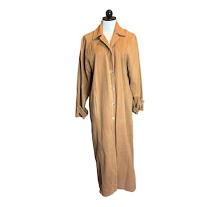 May include: A tan-colored, full-length coat with a button-up front and long sleeves. The coat has a classic collar and a tailored fit, suitable for various occasions. The coat is displayed on a mannequin.