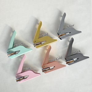 May include: Five different colored metal stampers with a round seal. The colors are green, gold, silver, rose gold, and pink.