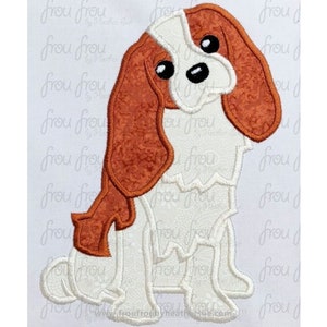 Puede incluir: Parche bordado de un perro Cavalier King Charles Spaniel de dibujos animados. El perro es blanco con orejas marrones y una mancha marrón en la espalda. El perro está sentado con la cabeza inclinada hacia un lado.