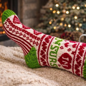 May include: A knitted sock with a festive design, featuring red, white, and green colors. The sock has a patterned design with the word "Mrs" in green. The sock is on a soft, textured surface.