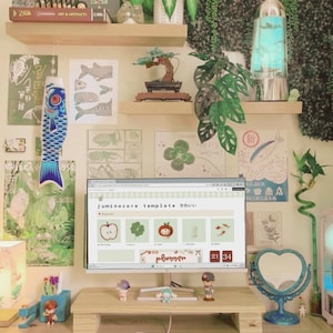 May include: A computer monitor displaying a juminocore template website with icons of an apple, clover, mushroom, and goldfish. The desk setup includes a wooden monitor stand, a white keyboard, a blue heart-shaped mirror, and various wall art.