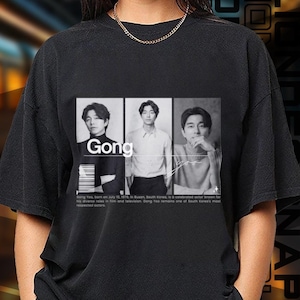 May include: Black t-shirt with a graphic of three men in black and white. The graphic includes the text "Gong".