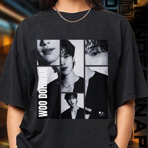 May include: Black t-shirt with a graphic print of a group of people. The print features the text "Woo Do Hwan" and the people's faces are in black and white.