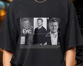 May include: Black t-shirt featuring a grayscale image of an actor with the name "Eric" and the last name "Dane". The shirt includes a short biography and a barcode design.