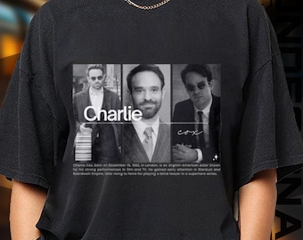 May include: Black t-shirt featuring a grayscale image of actor Charlie Cox. The image is divided into three sections, with the name "Charlie" prominently displayed. Text at the bottom details his career.