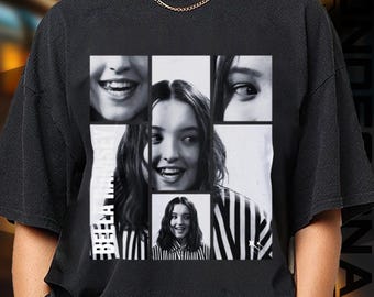 May include: Black t-shirt featuring a collage of black and white images of a person smiling. The collage includes close-ups of the person's eyes and mouth, along with a full-face image. The text "BELLA" is printed vertically on the left side.