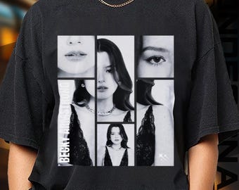 May include: Black t-shirt featuring a collage of black and white images of a person. The images include close-ups of the person's face and shoulders. The text "BECKY ARMSTRONG" is printed vertically on the left side of the shirt.