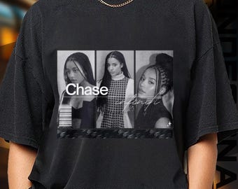 May include: Black t-shirt featuring a grayscale image of three women in individual frames. The word "Chase" is printed in white, and the word "infinity" is written in cursive. The shirt has a crew neck and short sleeves.