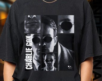 May include: Black t-shirt featuring a grayscale collage of a person wearing sunglasses. The text "CHARLIE COX" is printed vertically on the left side. The design includes multiple images of the person's face and upper body.