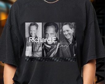 May include: Black t-shirt featuring a black and white image of Richard E. Grant. The image is divided into three sections, with the name "Richard E. Grant" printed in white. The shirt has a crew neck and short sleeves.