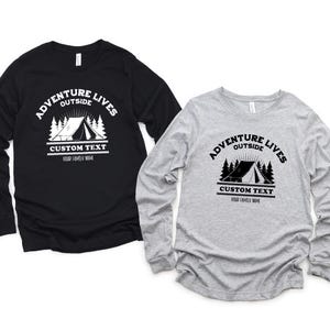May include: Two long-sleeve shirts, one black and one gray, featuring a camping-themed graphic. The design includes the text "Adventure Lives Outside" above a tent and trees, with space for custom text below.