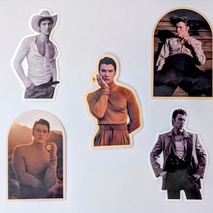 May include: A collection of five die-cut stickers featuring images of a person in various poses and outfits. The stickers include a cowboy hat, a turtleneck, and a blazer. The color palette includes shades of brown, white, and black.