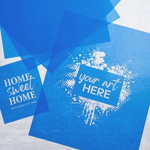 May include: Blue stencil sheets with white text. One sheet says "Home sweet home" with the text "Swansons Est 2020" below. The other sheet has a white splatter design with a rectangle in the center that says "your art HERE".