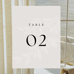 May include: A white table number card with a floral design and the text "TABLE 02" in black.