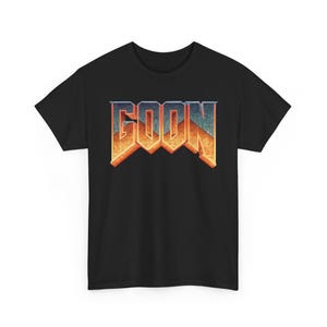 Könnte beinhalten: Schwarzes T-Shirt mit dem Wort "GOON" in einem stilisierten Farbverlauf. Der Text wechselt von Orange zu Blau und erzeugt ein auffälliges Design. Das Shirt hat einen klassischen Rundhalsausschnitt.