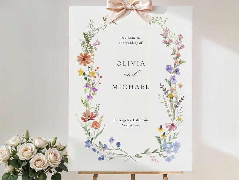 May include: A white wedding welcome sign with a floral wreath border. The sign reads "Welcome to the wedding of Olivia and Michael, Los Angeles, California, August 2023".