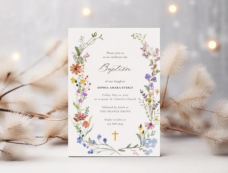 Op de afbeelding: Een bloemige doop uitnodiging met een witte achtergrond en een krans van kleurrijke wilde bloemen. De tekst luidt: "U bent van harte welkom om samen met ons de doop van onze dochter Sophia Amara Everly te vieren, op vrijdag 10 mei 2015 om 10:00 uur in de St. Gabriel's Church, gevolgd door een lunch in The Orange Grove. Reageer naar Julia op 555 888 5643."