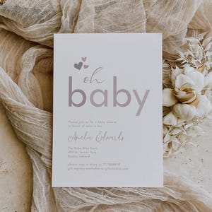 May include: A white baby shower invitation with pink hearts and the text "oh baby" in a pink gradient. The invitation includes the name "Amelia Edwards" and details for the shower, including the location, date, and RSVP information.