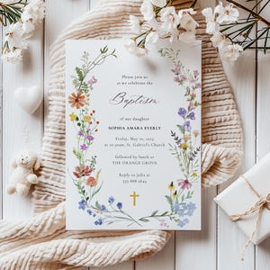 Op de afbeelding: Een bloemige doop uitnodiging met een aquarel krans van bloemen en groen. De tekst luidt "U bent van harte welkom om de doop van onze dochter Sophia Amara Everly te vieren Vrijdag 10 mei 2025 om 10:00 uur, St. Gabriel's Church gevolgd door een lunch in THE ORANGE GROVE Reageer naar Julia op 555 888 5643".
