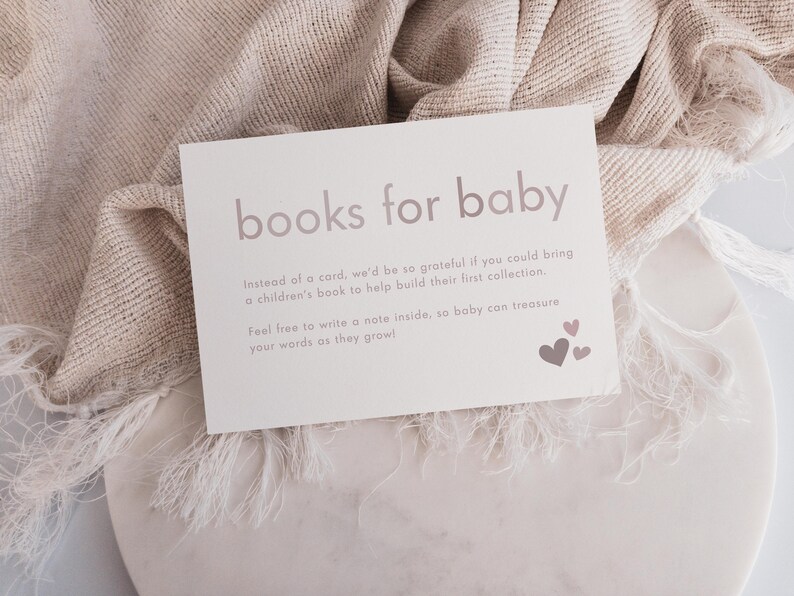 May include: A white card with the text "books for baby" in pink lettering. The card has a message asking guests to bring a children's book instead of a card for the baby. The card is decorated with pink hearts.