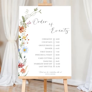 May include: A white sign with a floral border and a black and white list of wedding events with corresponding times. The sign reads "Order of Events" and includes events like "Ceremony", "Cocktails", "Dinner", "First Dance", "Speeches & Toast", "Cake Cutting", "Dancing", "Sparkler Send Off", and "Last Shuttle".