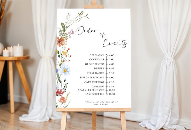 May include: A white sign with a floral border and a black and white list of wedding events with corresponding times. The sign reads "Order of Events" and includes events like "Ceremony", "Cocktails", "Dinner", "First Dance", "Speeches & Toast", "Cake Cutting", "Dancing", "Sparkler Send Off", and "Last Shuttle".