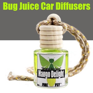 May include: A green glass car air freshener with a wooden cap and a gold string. The label reads "Mango Delight" with a green butterfly and the text "Smells So Good".