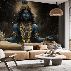 May include: A blue and gold deity with closed eyes sits in a meditative pose against a dark blue and gold background. The deity is adorned with jewelry and a peacock feather headdress.