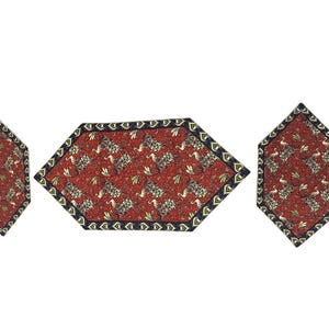 May include: A set of three decorative table mats. The mats have a red background with a floral pattern in gold and black. The edges are trimmed with a dark blue border. The mats are in a hexagonal shape.