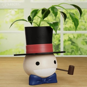 May include: A white planter shaped like a person's head wearing a black top hat with a red band, a blue bow tie, and a brown pipe. The planter has a green plant growing out of the top hat.