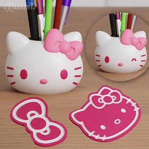 May include: A white desk organizer shaped like a cat's head with a pink bow, pink nose, and pink accents. The organizer holds pens and pencils. Two pink bow-shaped coasters and a cat-shaped coaster are also visible.