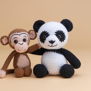 Puede incluir: Un oso panda de peluche y un mono de peluche tejidos a crochet. El panda es negro y blanco con una cara blanca y ojos negros. El mono es marrón con una cara rosa y ojos marrones.