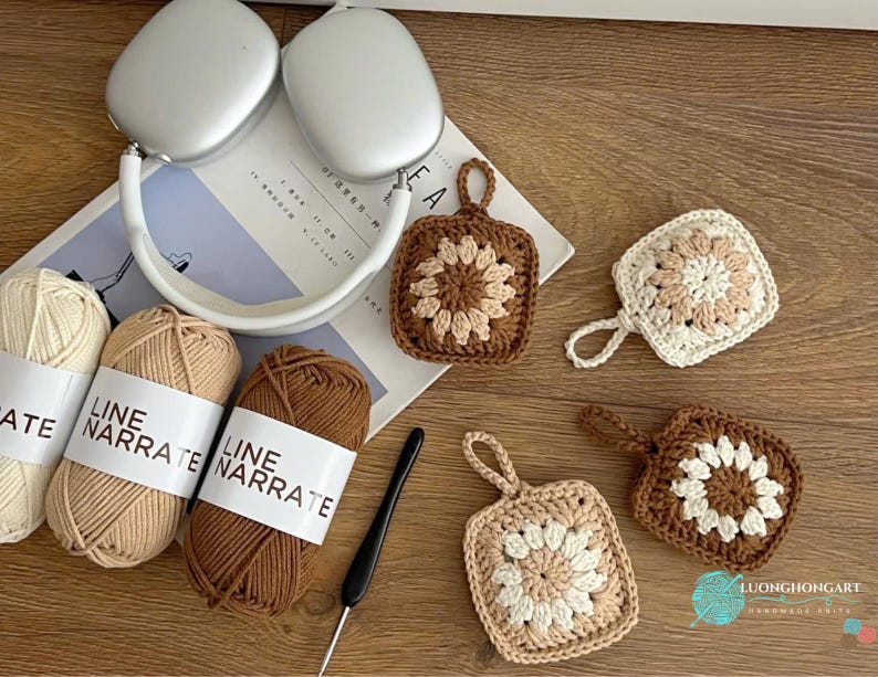 Puede incluir: Tres ovillos de hilo Line Narrate en crema, beige y marr&oacute;n, un ganchillo negro, auriculares plateados y cuatro posavasos cuadrados de ganchillo con un patr&oacute;n de flores en colores a juego y peque&ntilde;as asas para colgar.
