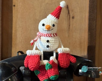 Può includere: Un pupazzo di neve all'uncinetto fatto a mano con cappello, sciarpa, guanti e calzini rossi e bianchi. Il pupazzo di neve ha un naso a carota e occhi a bottone neri. Decorazione invernale.