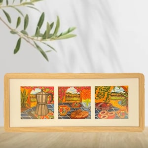 May include: A framed artwork featuring three colorful panels. The panels depict a coffee pot, a cup and pastries, and a plate of cookies. The artwork has a light wood frame and is set against a neutral background.