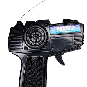 May include: Black remote control with the brand name "NIKKO" displayed on the front. The remote has a trigger, antenna, and a textured grip. The text "MADE IN CHINA" is visible on the bottom.