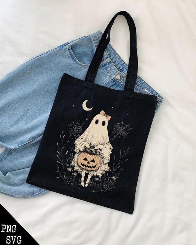 May include: Black canvas tote bag featuring a white ghost holding a jack-o'-lantern. The ghost has a pink bow on its head and is surrounded by cobwebs and stars.
