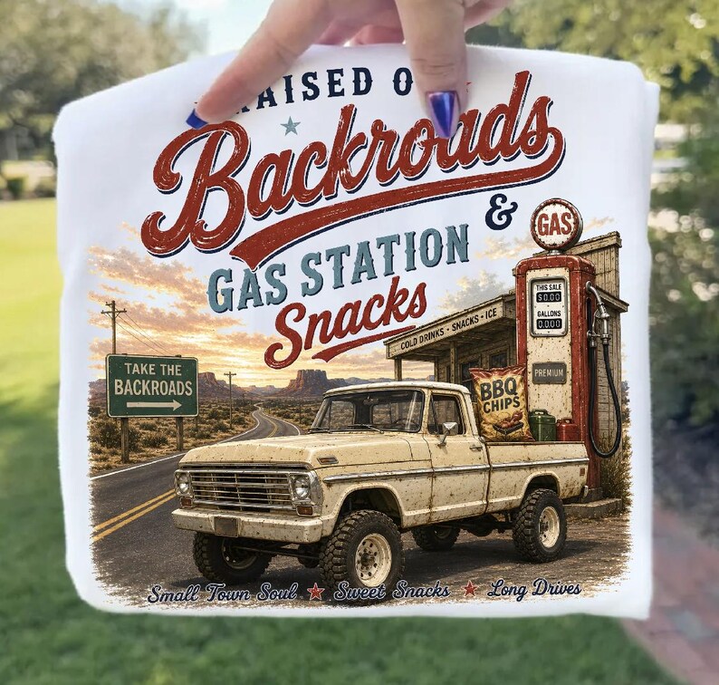 May include: White t-shirt featuring a vintage design with the words "Raised on Backroads Gas Station Snacks." The graphic includes a classic pickup truck, gas pump, and a desert road scene. The shirt also has the text "Take the Backroads."