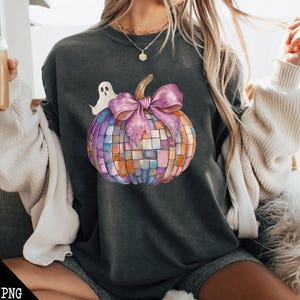 May include: A dark gray sweatshirt with a colorful mosaic pumpkin design. The pumpkin has a pink bow and a white ghost is behind it.