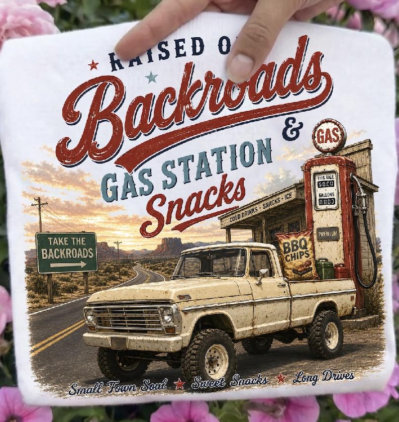 May include: White t-shirt with a vintage graphic of a beige pickup truck at a gas station, with the text "RAISED ON Backroads GAS STATION Snacks". Includes a sign that says "TAKE THE BACKROADS". Also has the text "Small Town Soul Sweet Snacks Long Drives".