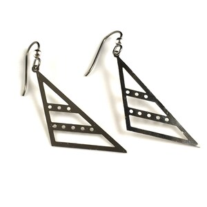 May include: A pair of silver triangle earrings with a geometric design and a dotted pattern.