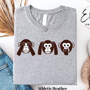 May include: A gray t-shirt with the three wise monkeys saying "See no evil, hear no evil, speak no evil". The monkeys are brown and the text "Athletic Heather" is at the bottom of the shirt.