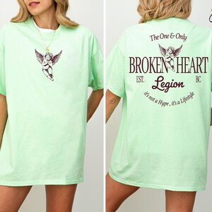 Mint green t-shirt with "Broken Heart Legion" graphic and cherub design.