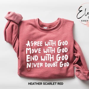 May include: Heather scarlet red sweatshirt with the text "Agree with God, Move with God, End with God, Never Doubt God" printed in white.