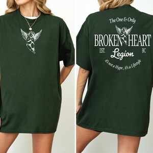 Dark green t-shirt with angel graphic and "Broken Heart Legion" text on back.