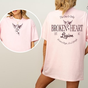 Pink t-shirt with angel graphic and "Broken Heart Legion" text.