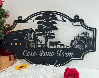 May include: Black metal sign featuring a farmhouse scene, including a barn, a tree, a tractor, and cows. The sign reads "Casa Luna Farm".